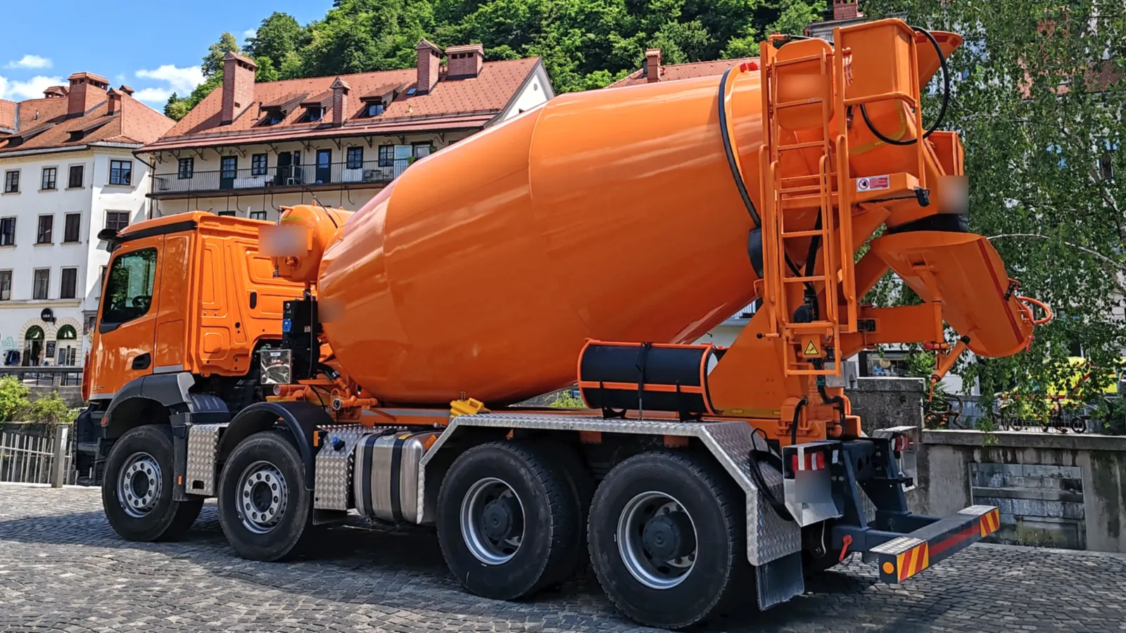 Mixer de concreto con el tambor naranja en una calle empedrada